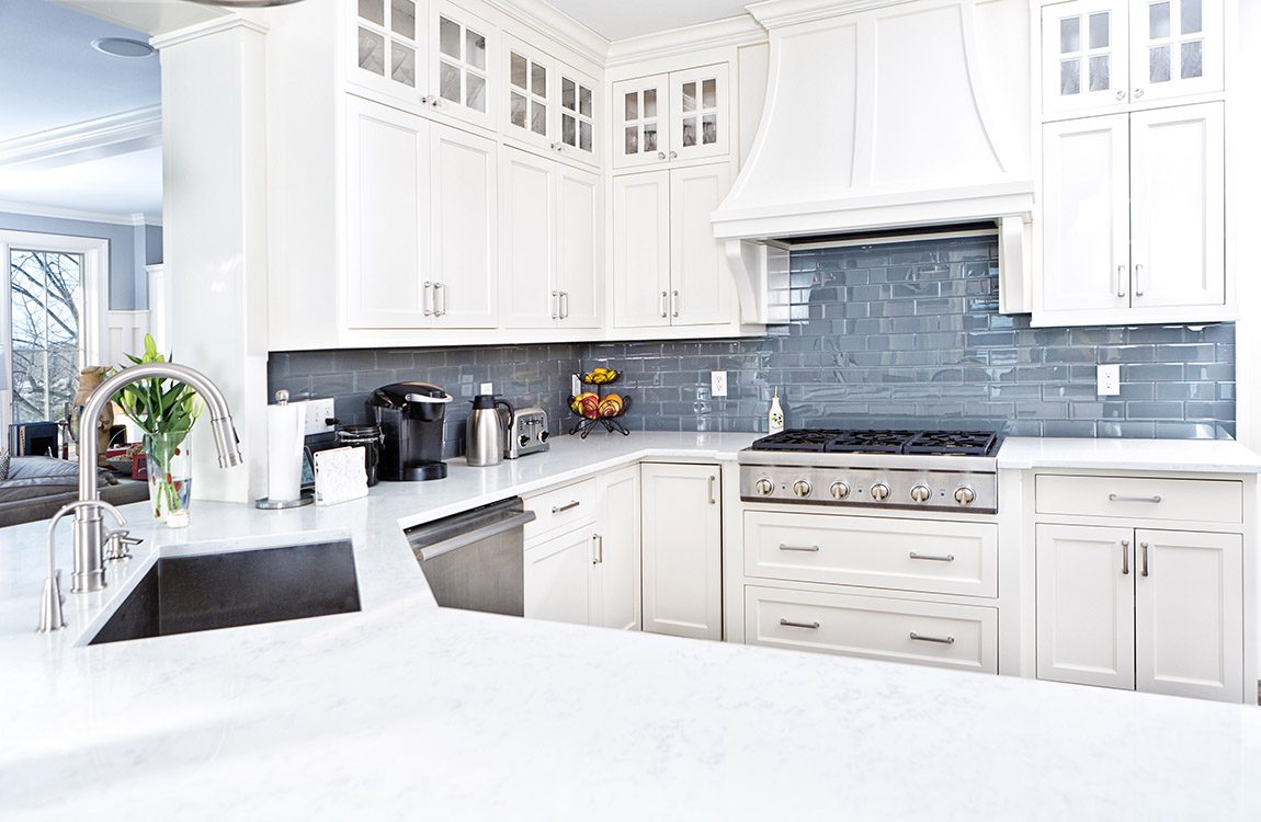 A contemporary home kitchen with stainless steel appliances and painted white cabinets.